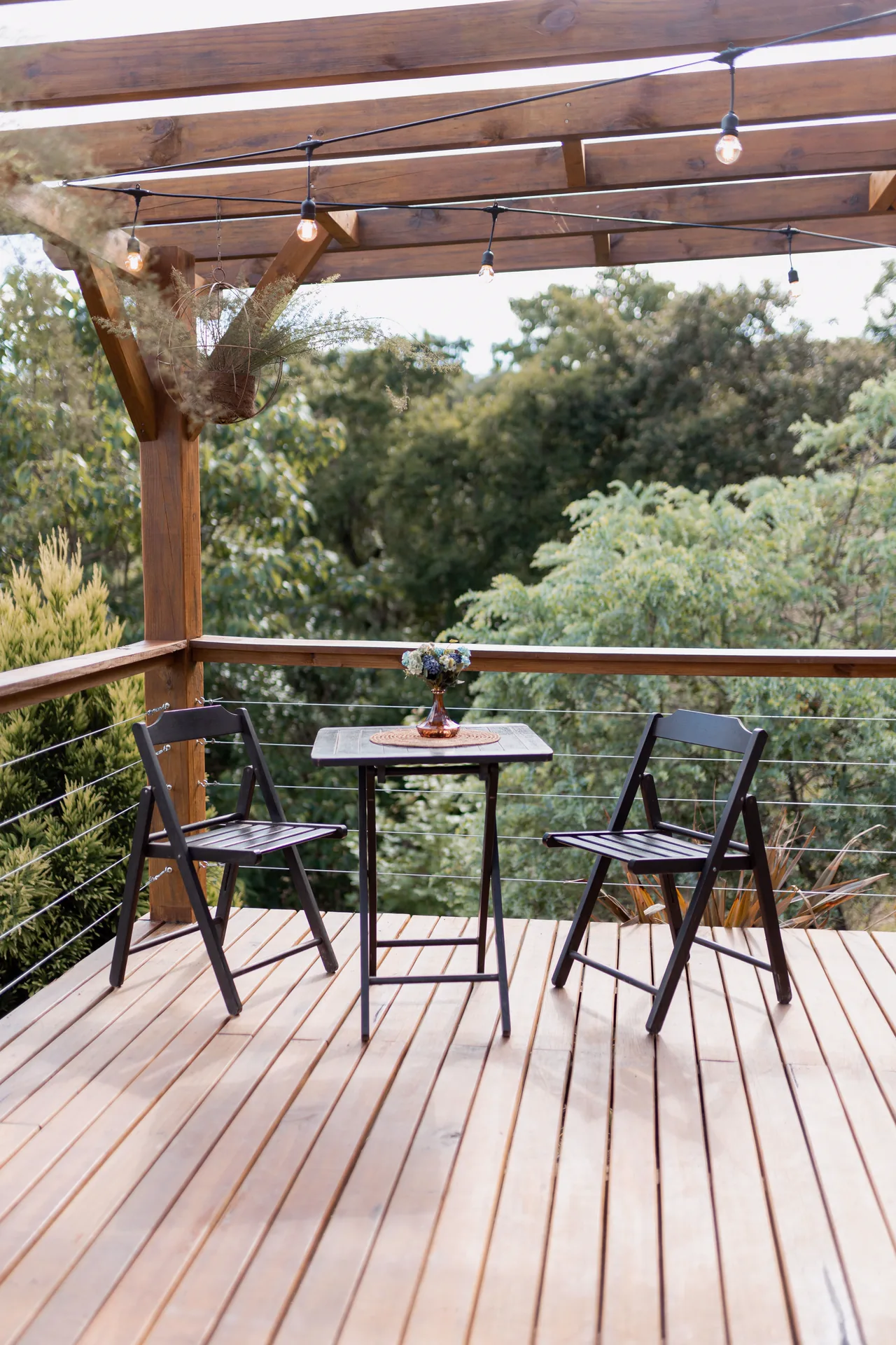 A wood deck under a pergola with string lights
