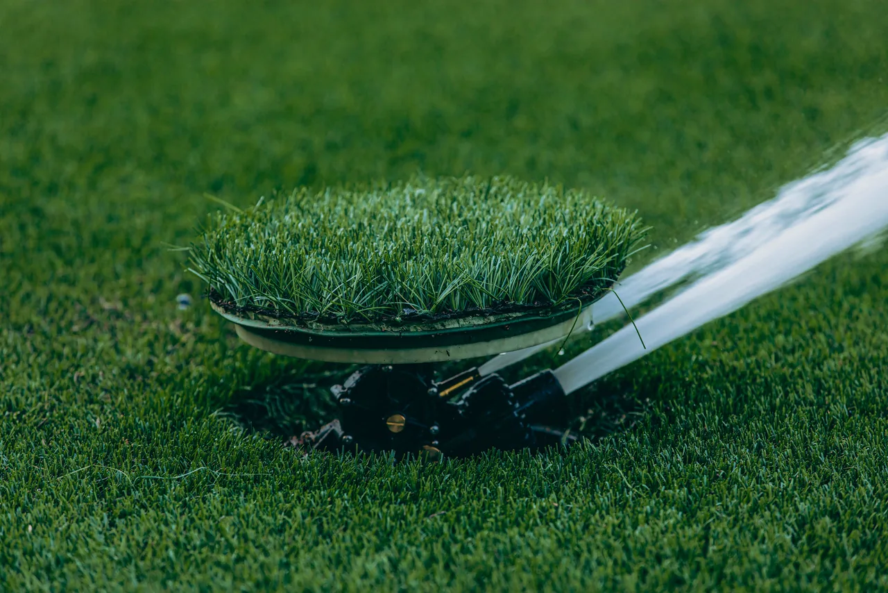 A sprinkler watering a green lawn